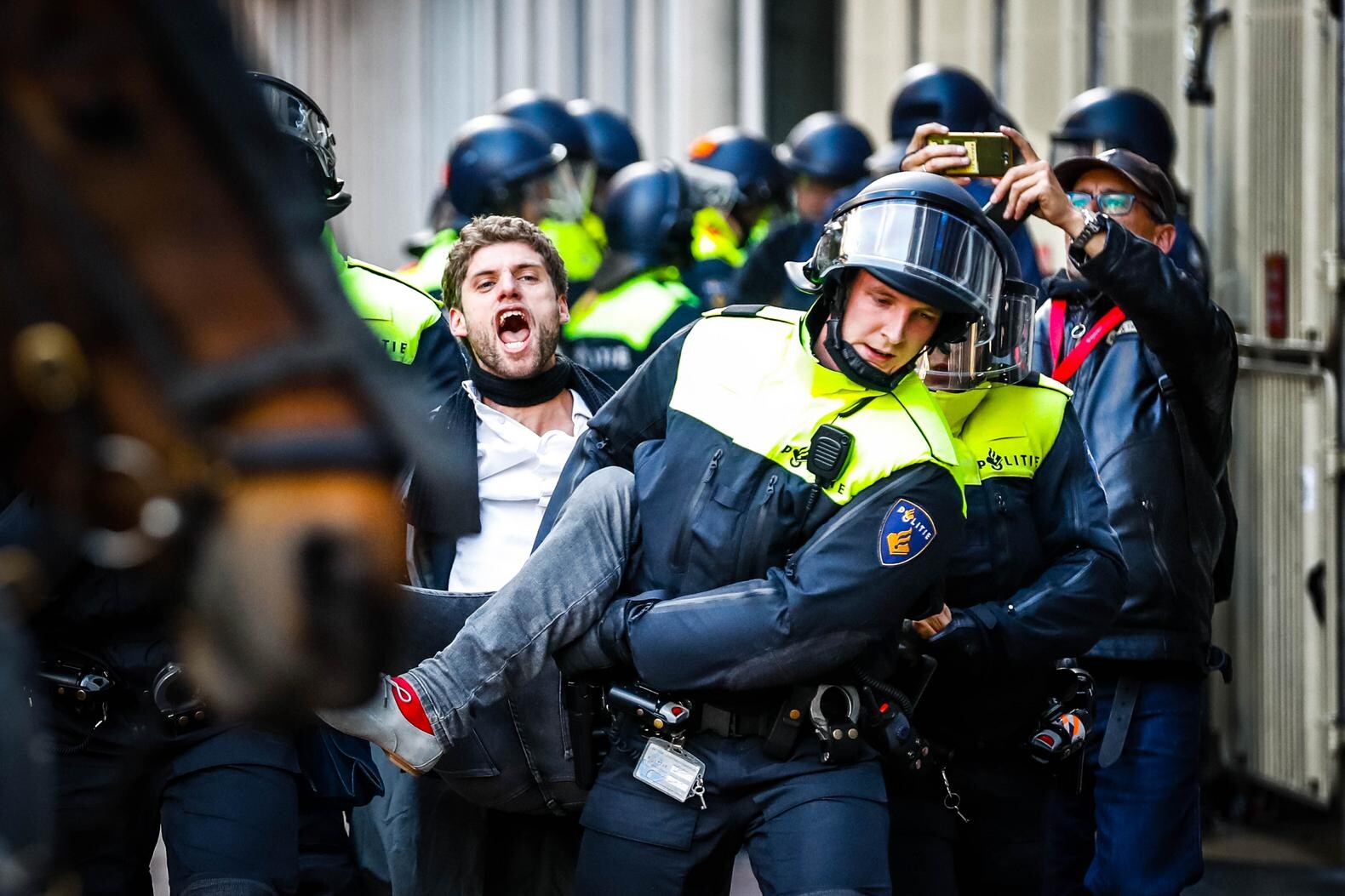 De bezetters worden door de politie een voor een uit het gebouw gehaald.