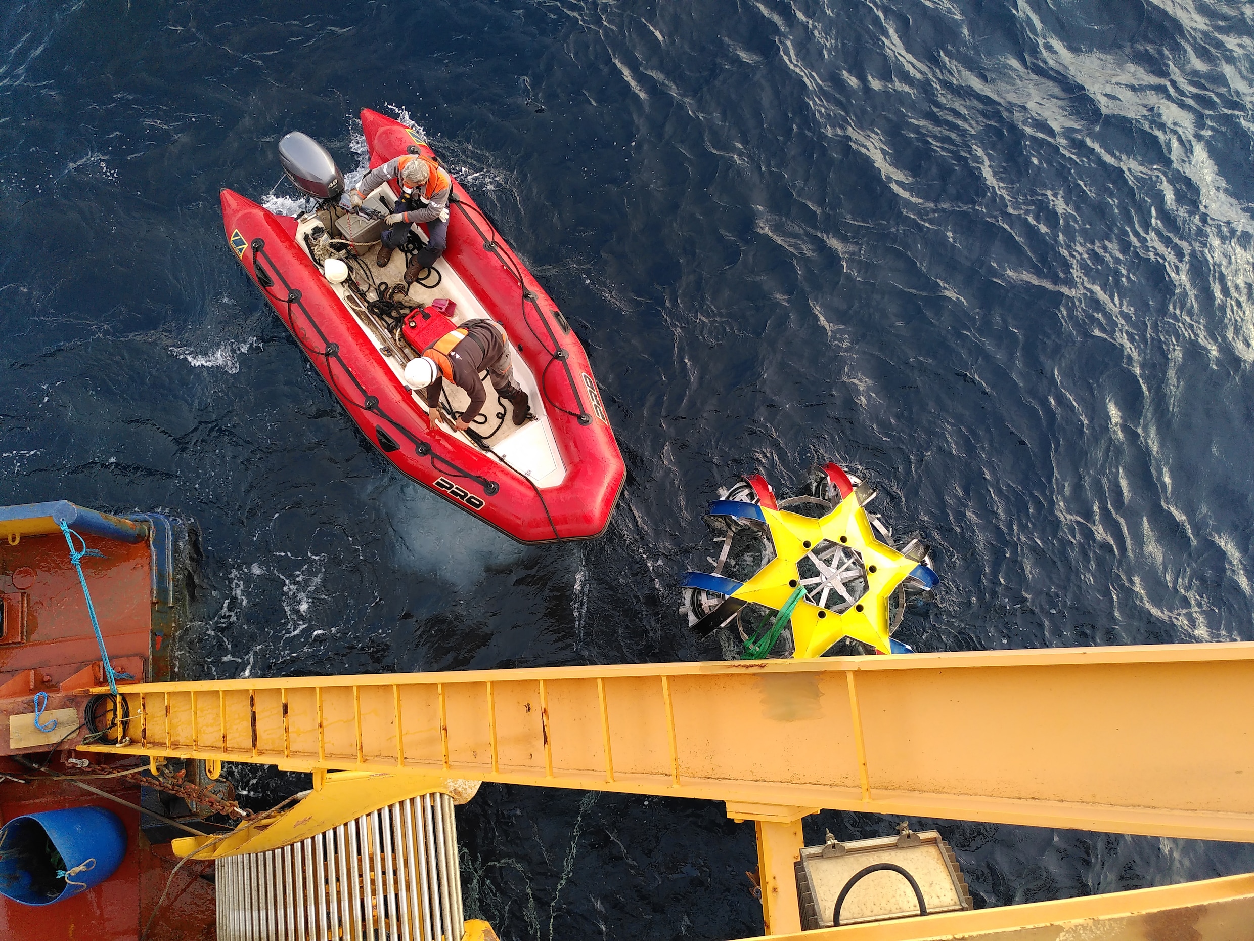 Onderzoekers laten een drijver met detector­bollen in de Middellandse Zee zakken. De drijver en de detectoren maken deel uit van de KM3NeT, waarmee naar neutrino’s wordt gespeurd.