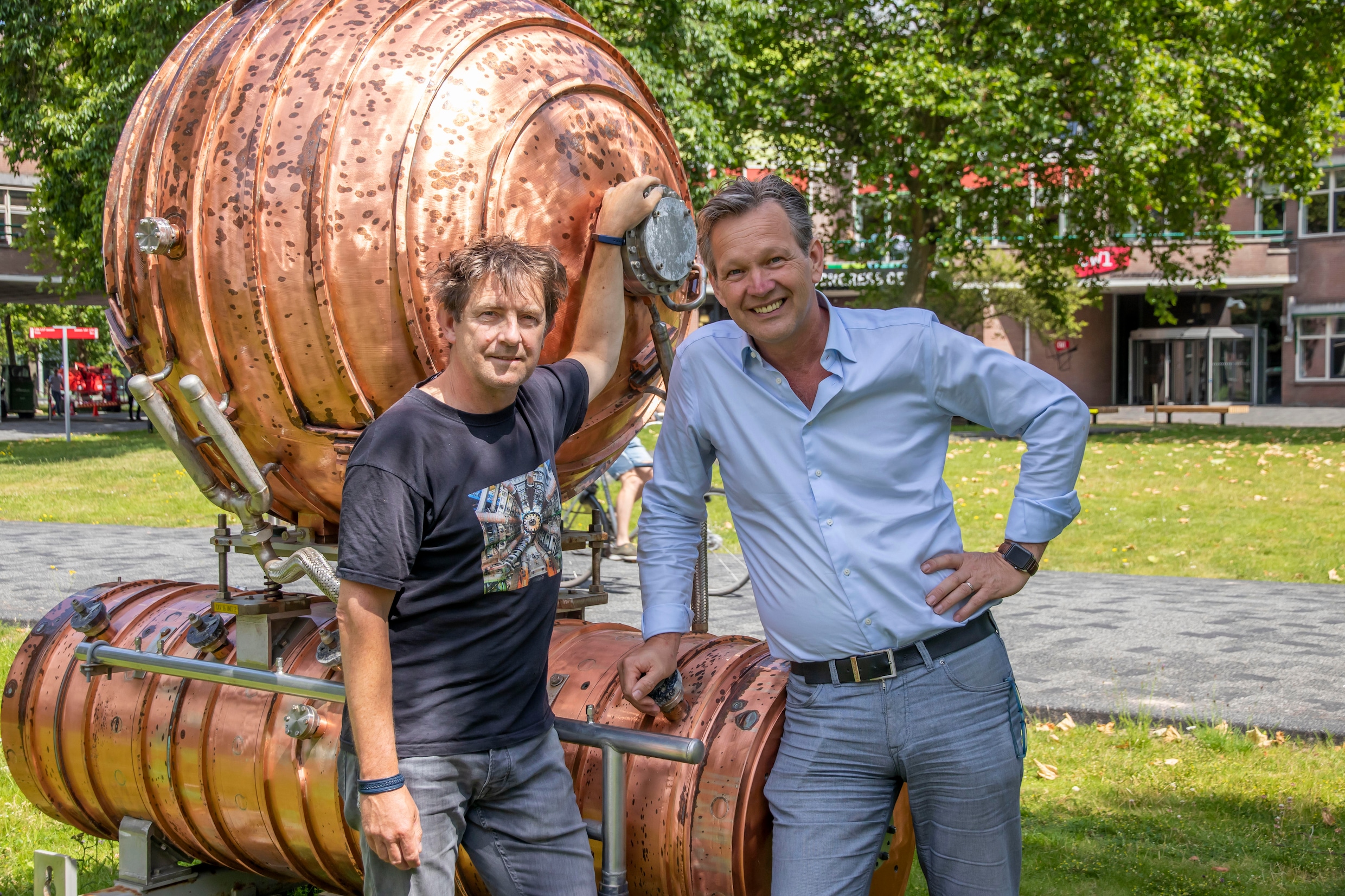 Martijn van Calmthout (l) en Stan Bentvelsen op het Science Park in Amsterdam met een onderdeel van de oude LEP-deeltjesversneller van CERN.