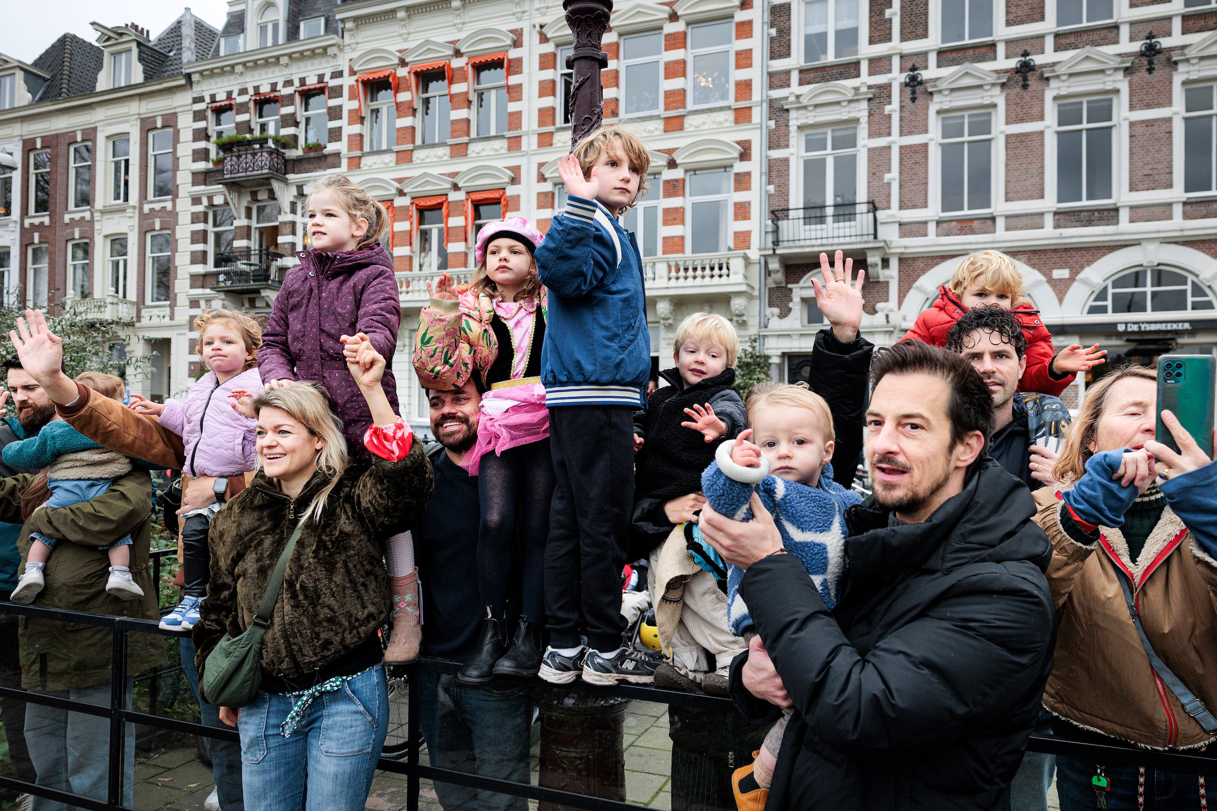 Vanaf de kant zwaaien kinderen en hun ouders naar Sinterklaas op het water