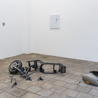 Exhibition A Good Hard Look: encounter between a dismantled scooter and a note from K. Schippers on a sidewalk tile